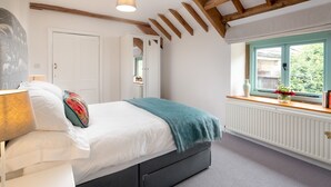 A bedroom with a bed, a window with a view, a radiator, and a ceiling with exposed beams. - Cotswolds Barn Apartment - luxury self catering near Bath & Bristo (Bristol)
