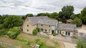 A stone house with a sloped roof, a front porch, and a driveway leading to a garage. - Cotswolds Barn Apartment - luxury self catering near Bath & Bristo (Bristol)