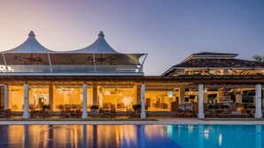 Un hôtel doté d’une piscine, d’un espace extérieur aménagé et d’une zone couverte avec un toit original.
