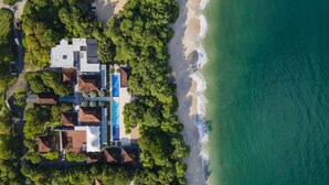 Vue aérienne d’une propriété située sur la côte, avec une piscine, plusieurs bâtiments et une plage.