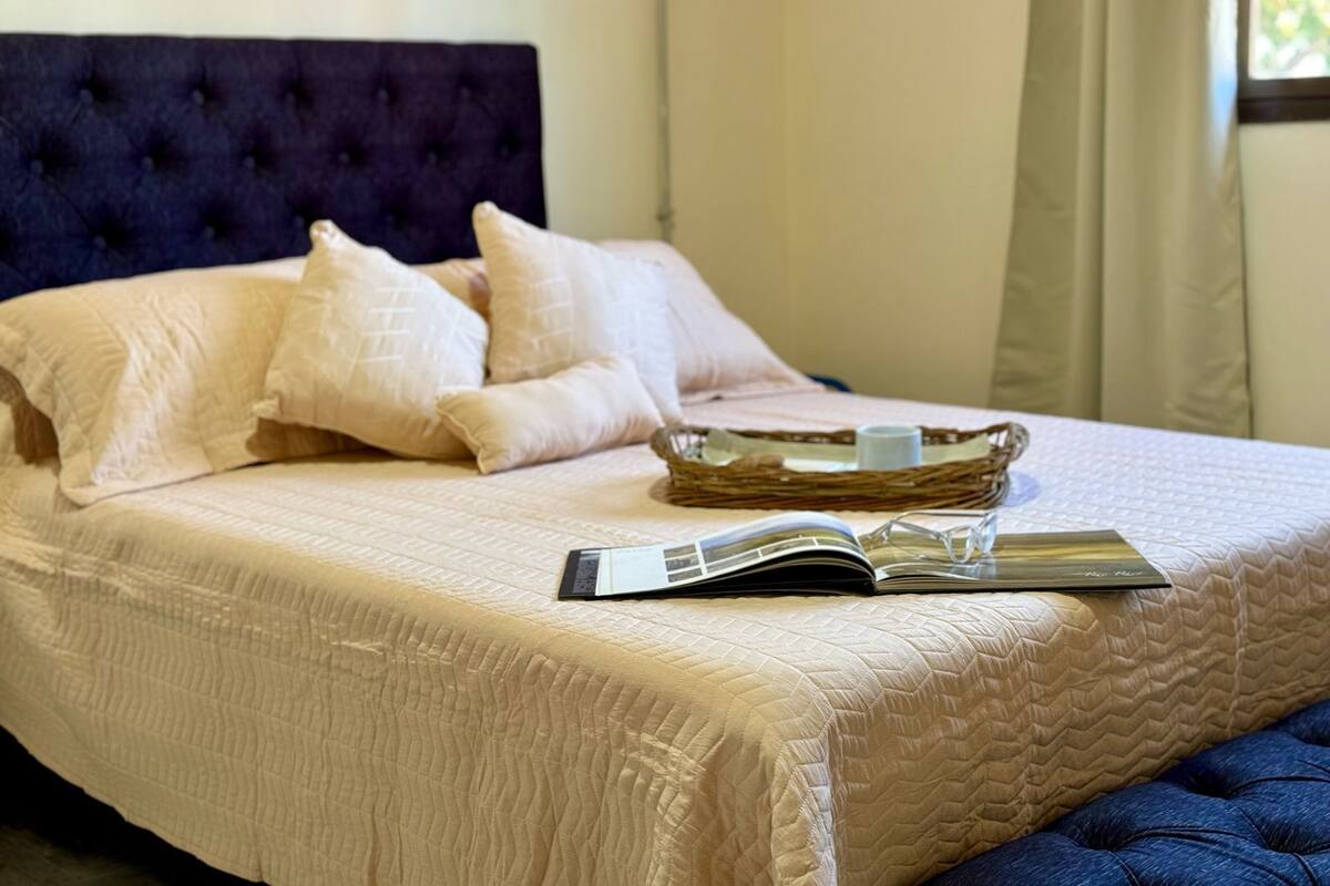 A neatly made bed with a quilted bedspread, a headboard, and several pillows.