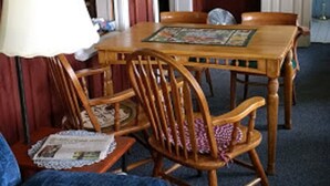 Un comedor con una mesa y sillas de madera, una lámpara y una puerta con espejo.