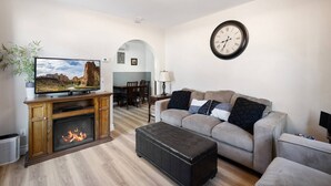 A living room with a fireplace, a television, a sofa, and a dining area with chairs. - Historic Drake Cottage - Walk to Downtown Bend - Drake Park Across the Street - Perfect for Couples (Bend)