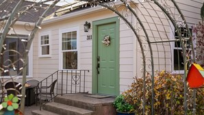 A house with a green door, steps leading to the entrance, and a small porch area with outdoor furniture. - Historic Drake Cottage - Walk to Downtown Bend - Drake Park Across the Street - Perfect for Couples (Bend)