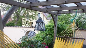 A wooden deck with a yellow hammock and a lantern.