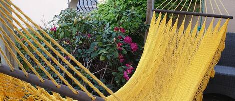 A wooden deck with a yellow hammock and a lantern.