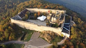 An aerial view of a historic fort with a large courtyard, a watchtower, and a bridge.