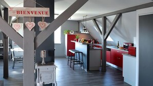 A modern kitchen with red cabinets, a central island, and a 'BIENVENUE' sign.