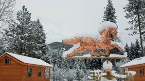 A wooden cabin with a snow-covered landscape, a large horse sculpture, and a sign with the letters "W" and "N". - The Ultimate Outdoor Adventure with Indoor Comfort (Darby)