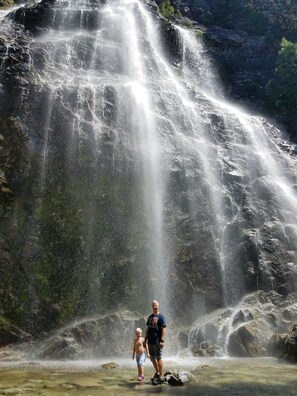 Una cascada con un hombre y un niño de pie frente a ella.