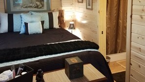 A cozy wooden cabin bedroom with a bed, a nightstand, a lamp, and framed artwork on the walls. - The Ultimate Outdoor Adventure with Indoor Comfort (Darby)