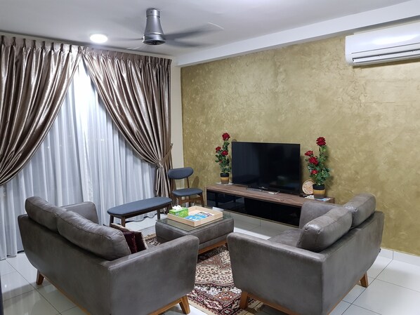 Relax in this stylish living room with a flat-screen TV, plush sofa, and armchair.