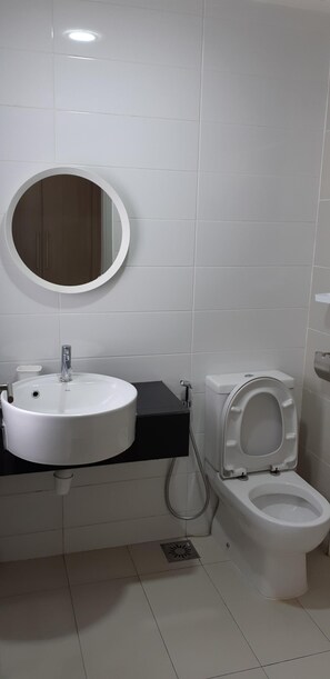 Bathroom features a white sink, round mirror, and a toilet with a lid.