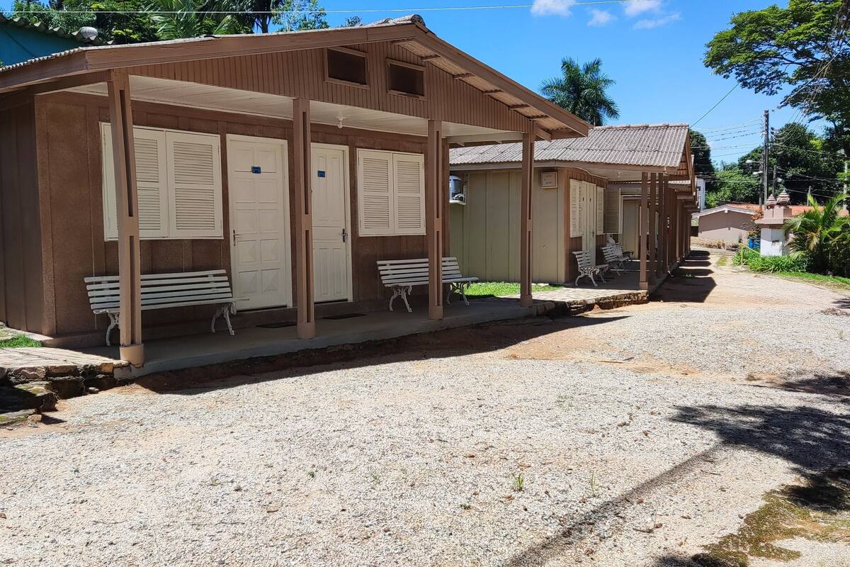 A building with a covered porch, two benches, and a gravel driveway.