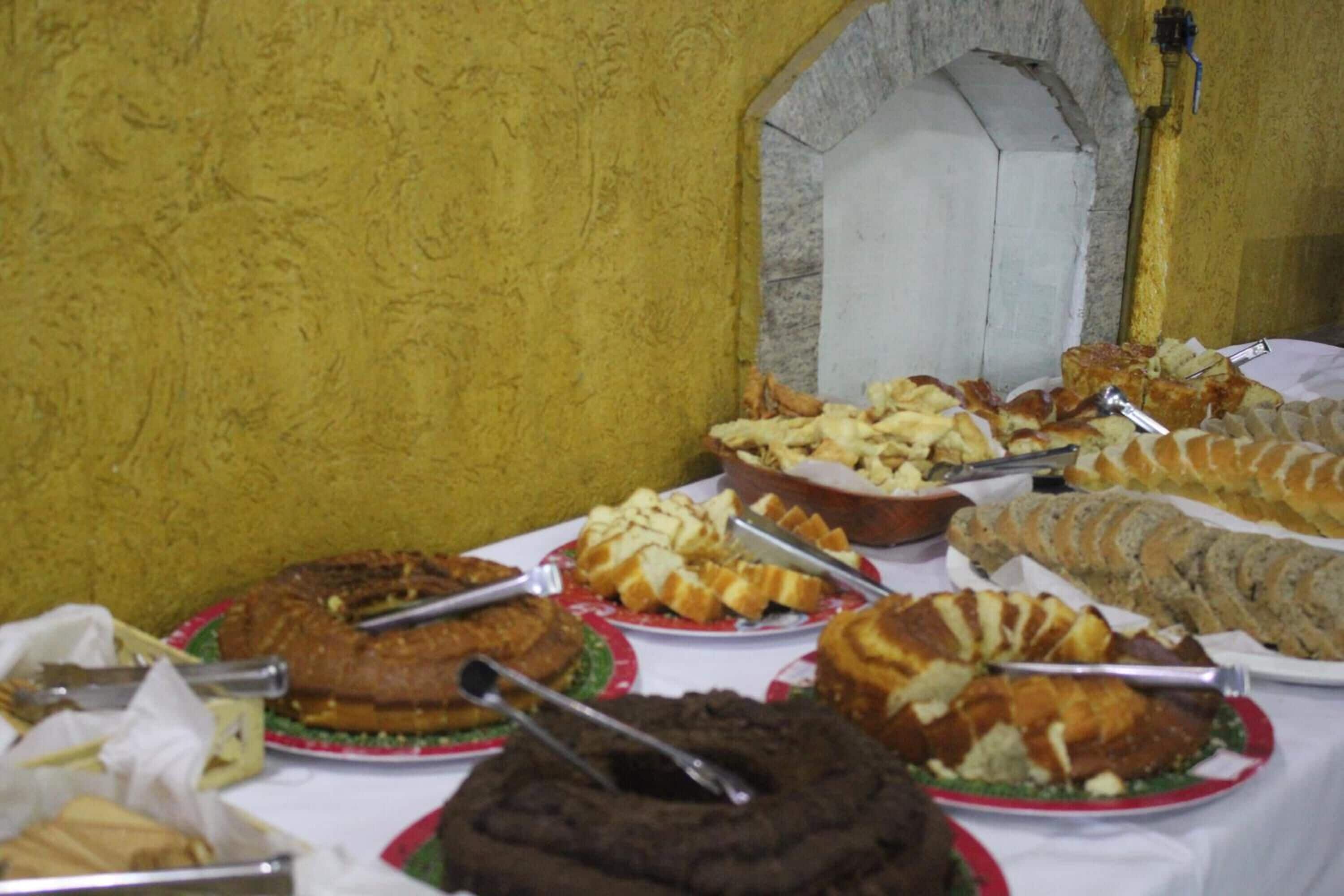 Una mesa con diversas opciones de panadería, como pasteles y dulces, presentados en platos con utensilios para servir.