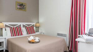 Une chambre d’hôtel bien rang ée, avec un lit, des tables de chevet, un bureau et un plateau de petit-déjeuner.