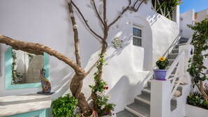Un bâtiment aux murs blancs, avec un escalier, un arbre et des plantes en pot.