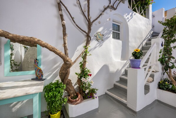 A white-walled building with a staircase, a tree, and potted plants. - SantoriniParadise: TRADITIONAL APARTMENT in Oia (Oia)