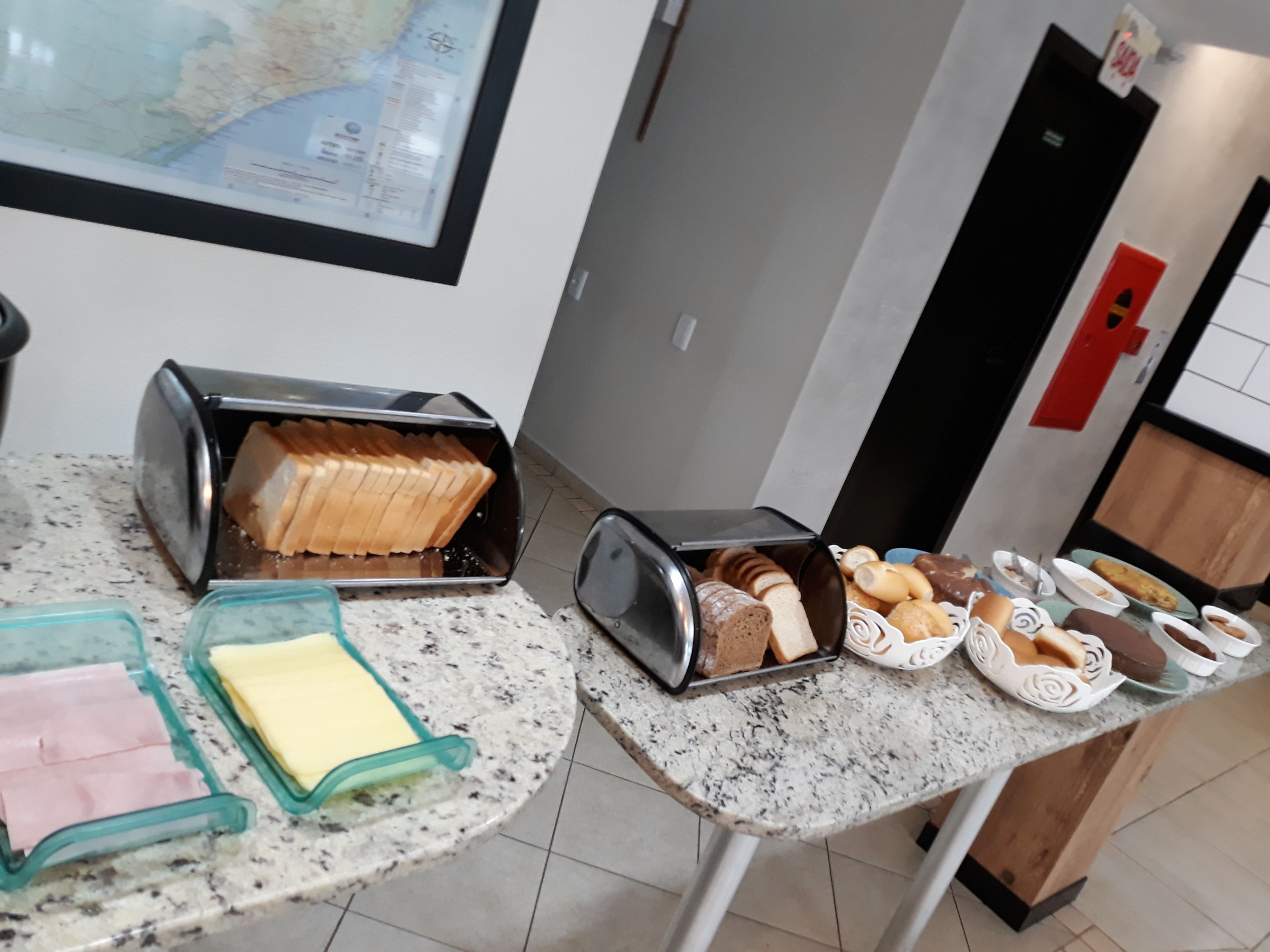 Una encimera de cocina con un tostador, una caja de pan y diversos panes y pasteles.