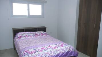 A bedroom with a bed, a window, and a wardrobe.