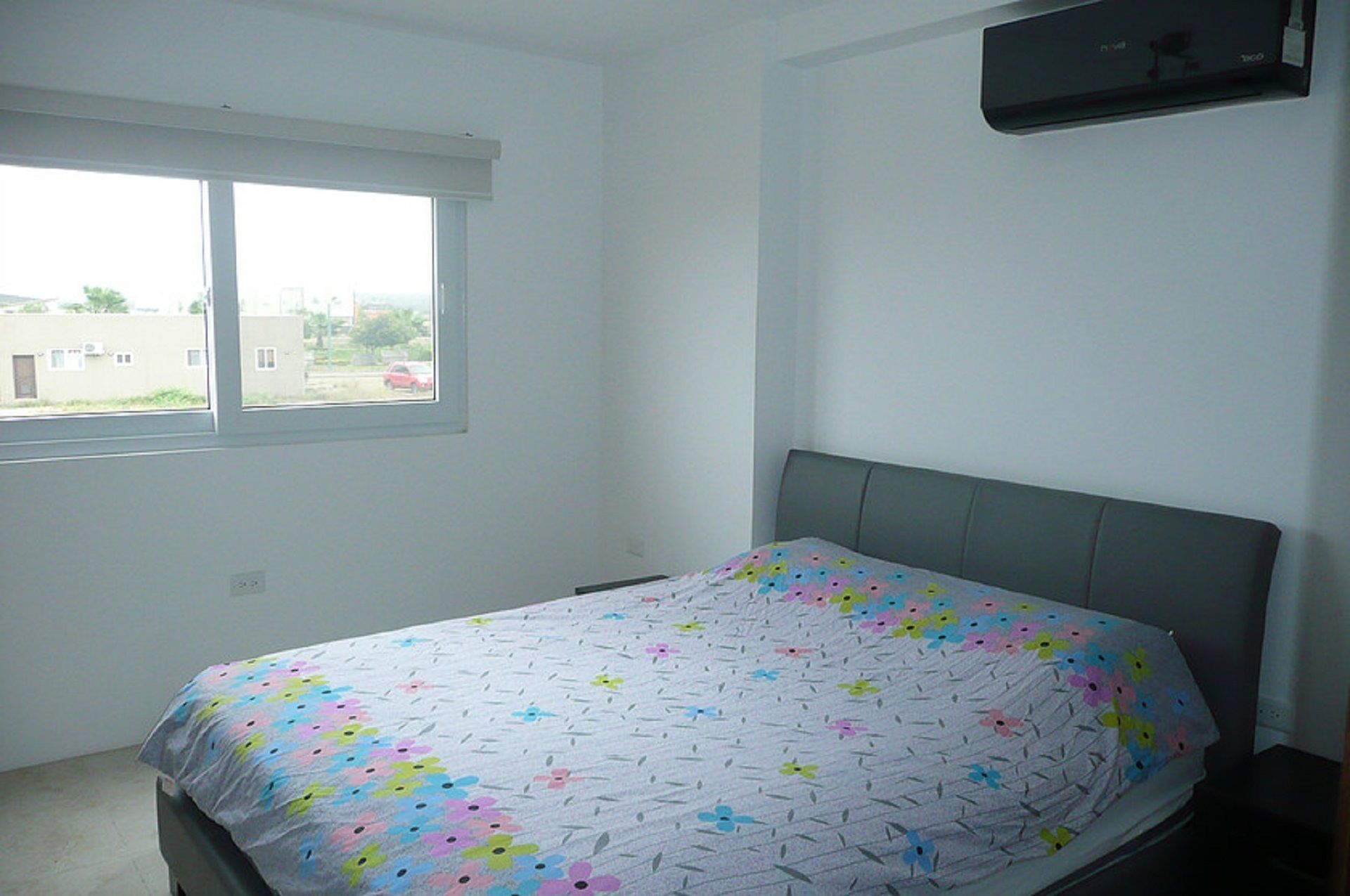 A bedroom with a bed, a window, and a wall-mounted air conditioner.