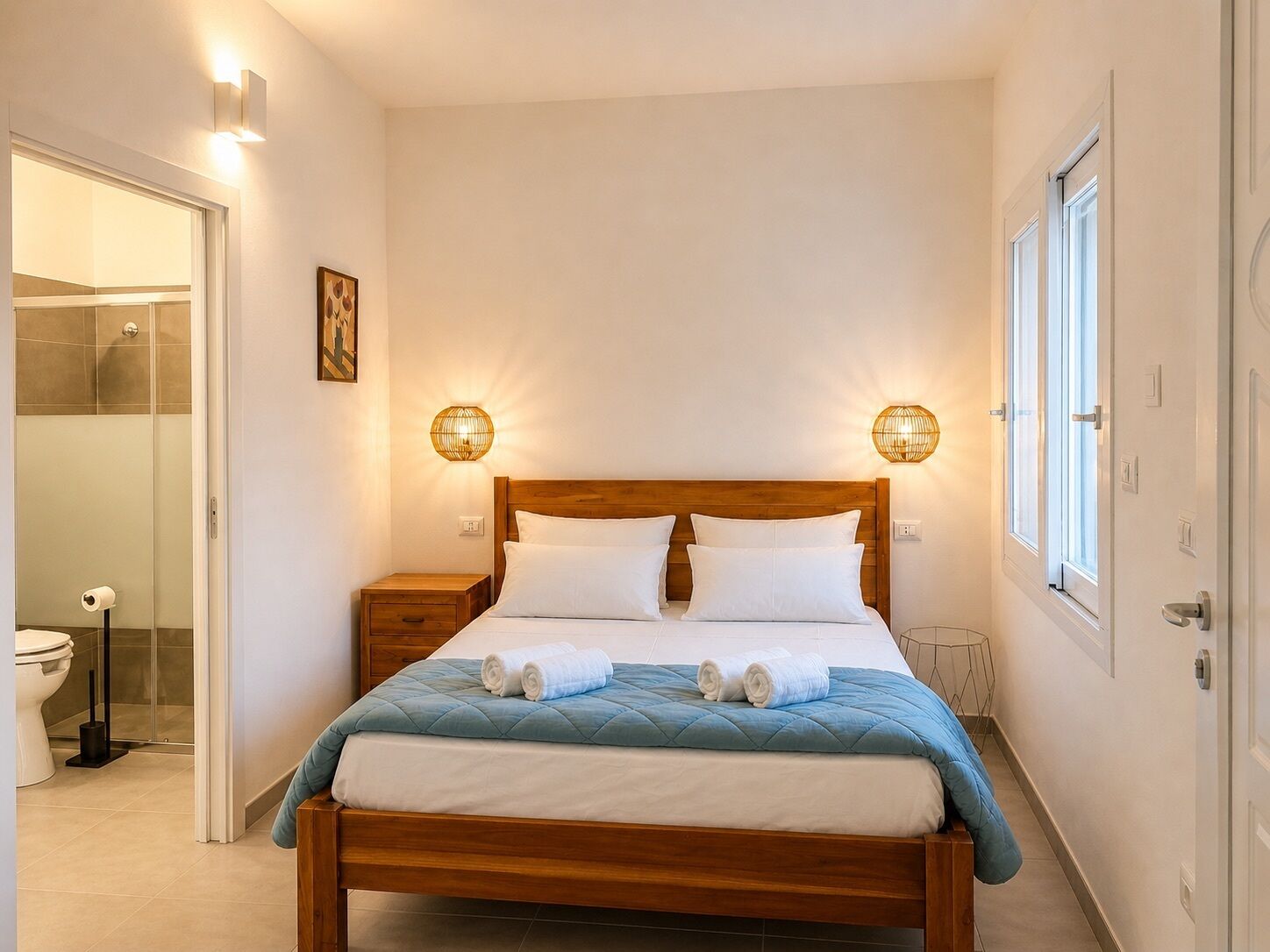 Quarto com cama de madeira, duas mesas de cabeceira, um criado-mudo, banheiro com vaso sanitário e chuveiro.