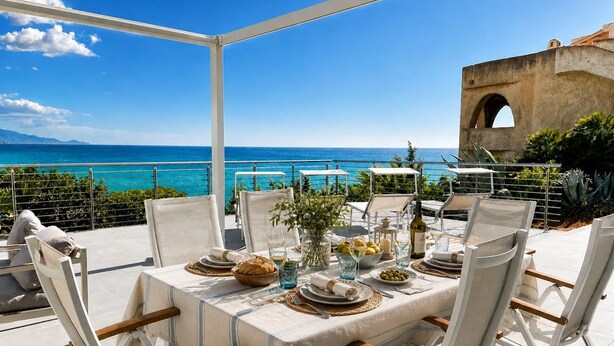 Un espace de restauration en plein air avec une table dressée pour quatre personnes, offrant une vue sur la côte.