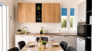 Une cuisine moderne avec des meubles en bois, une table à manger pour six personnes et un four encastré.
