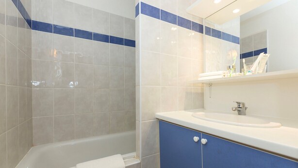 Une salle de bain avec une baignoire, un lavabo et un miroir.
