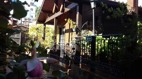 A traditional wooden building with a balcony, a metal railing, and potted plants. - Cabañas Valle Verde (Moya)