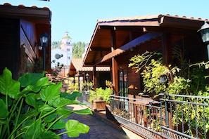 A wooden building with a balcony, potted plants, and a stone pathway. - Cabañas Valle Verde (Moya)