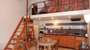 Une cuisine compacte avec des meubles en bois, une table à manger et un escalier menant à un niveau supérieur.