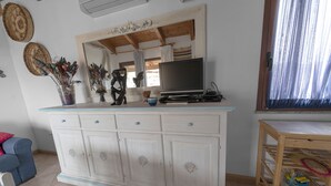 Una sala de estar con un mueble blanco, un televisor y objetos decorativos.
