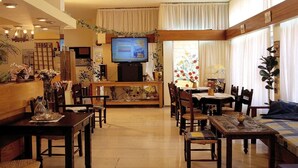 A hotel lobby with a television, dining area, and seating. - Aristea Hotel (Agios Nikolaos)