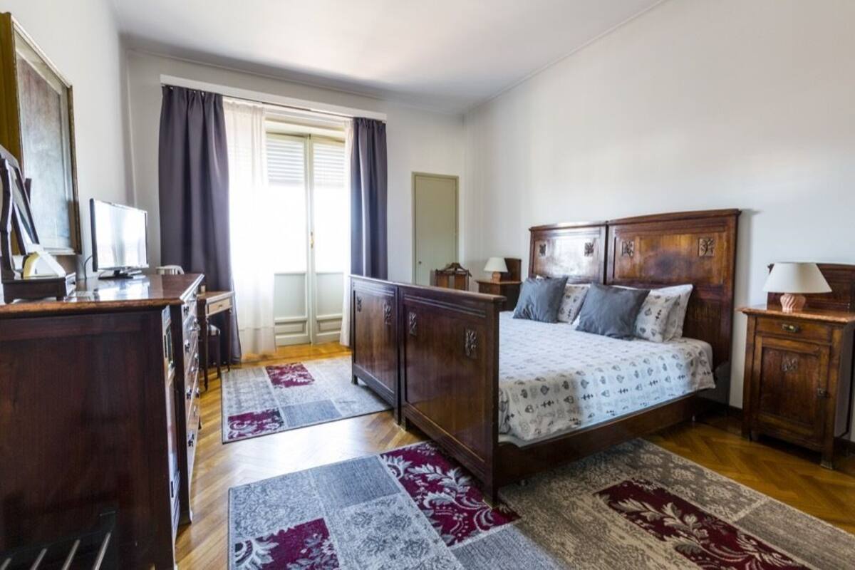 Un dormitorio con cama de madera, un escritorio, una silla, un televisor y un armario.