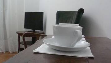A white cup and saucer on a table with a dark wood finish.