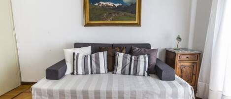 Un lit avec une literie à rayures, une tête de lit en bois et un tableau représentant des montagnes accroché au mur.