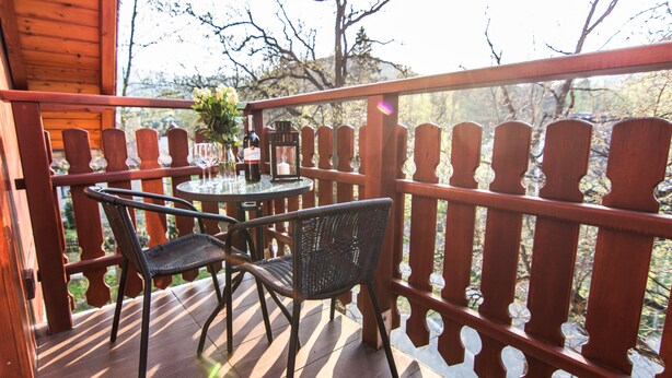 A wooden deck with a table and chairs, a bottle of wine, and a vase of flowers. - Apartamenty hoteLOVE pod Debami (Karpacz)