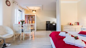 A hotel room with a bed, a desk, a chair, and a kitchenette. - Apartamenty hoteLOVE pod Debami (Karpacz)