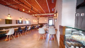 Un café spacieux, doté d’un mobilier moderne, d’un mur en briques et d’un présentoir à desserts.