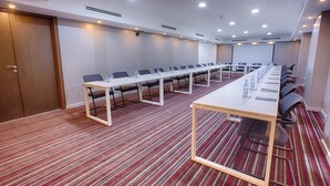 Une salle de conférence équipée d’une longue table, de chaises et d’un écran de projection.