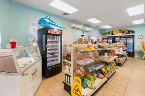 Um supermercado com balcão refrigerado, prateleiras repletas de lanches e diversos produtos.