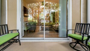 A sliding glass door leading to a patio with two rocking chairs and a dining table. - Magnolia Style Condo at Windsor Hills with Disney Theme Bunk Room (Kissimmee)