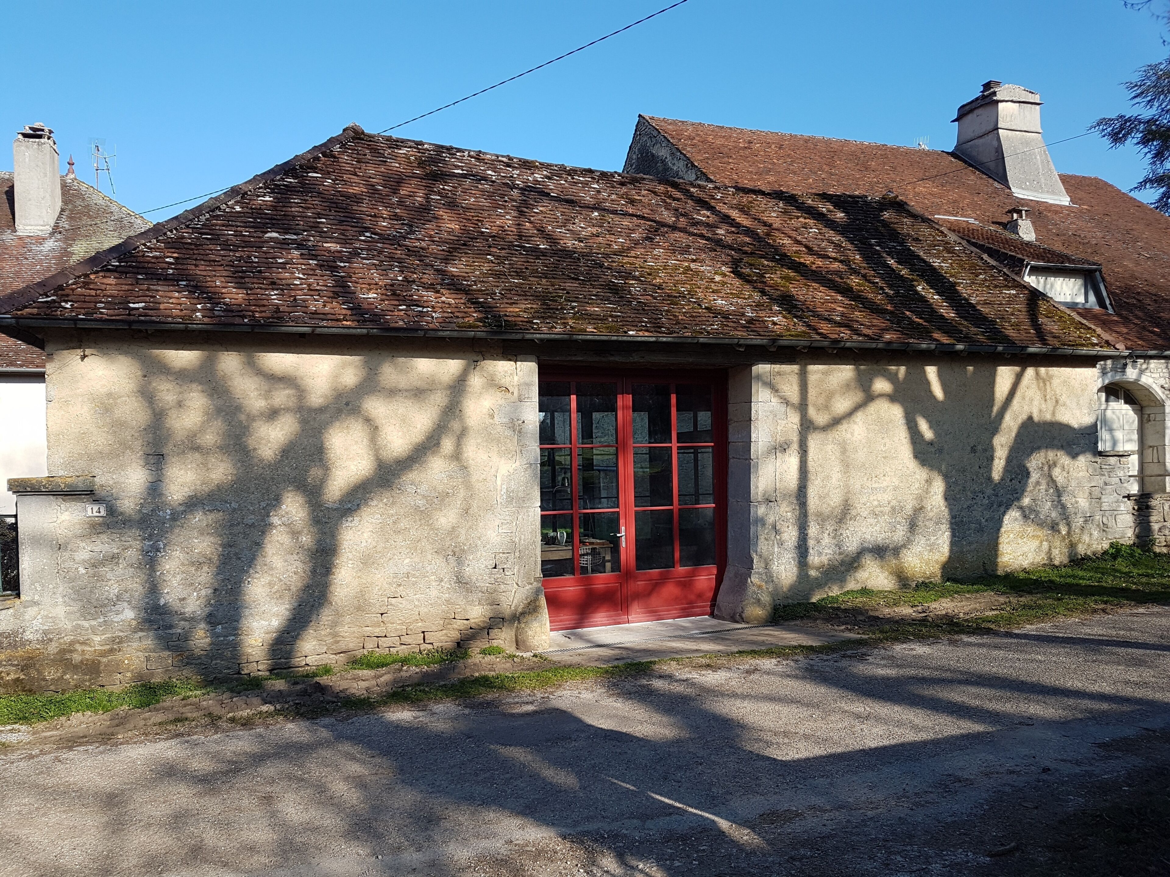 A small, single-story building with a red door and a sloped roof.