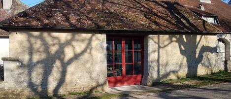 A small, single-story building with a red door and a sloped roof.