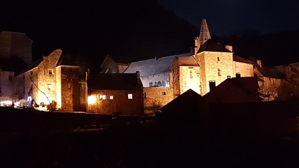A historic stone building with multiple towers and a prominent central tower, illuminated by artificial lighting. - Beautiful view of Baume les Messieurs (Baume les Messieurs)