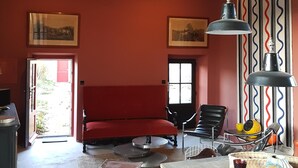 A rustic room with exposed wooden beams, a red sofa, a dining table with chairs, and pendant lighting. - Beautiful view of Baume les Messieurs (Baume les Messieurs)