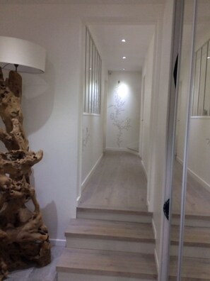 Un couloir avec un escalier en bois menant à une pièce.