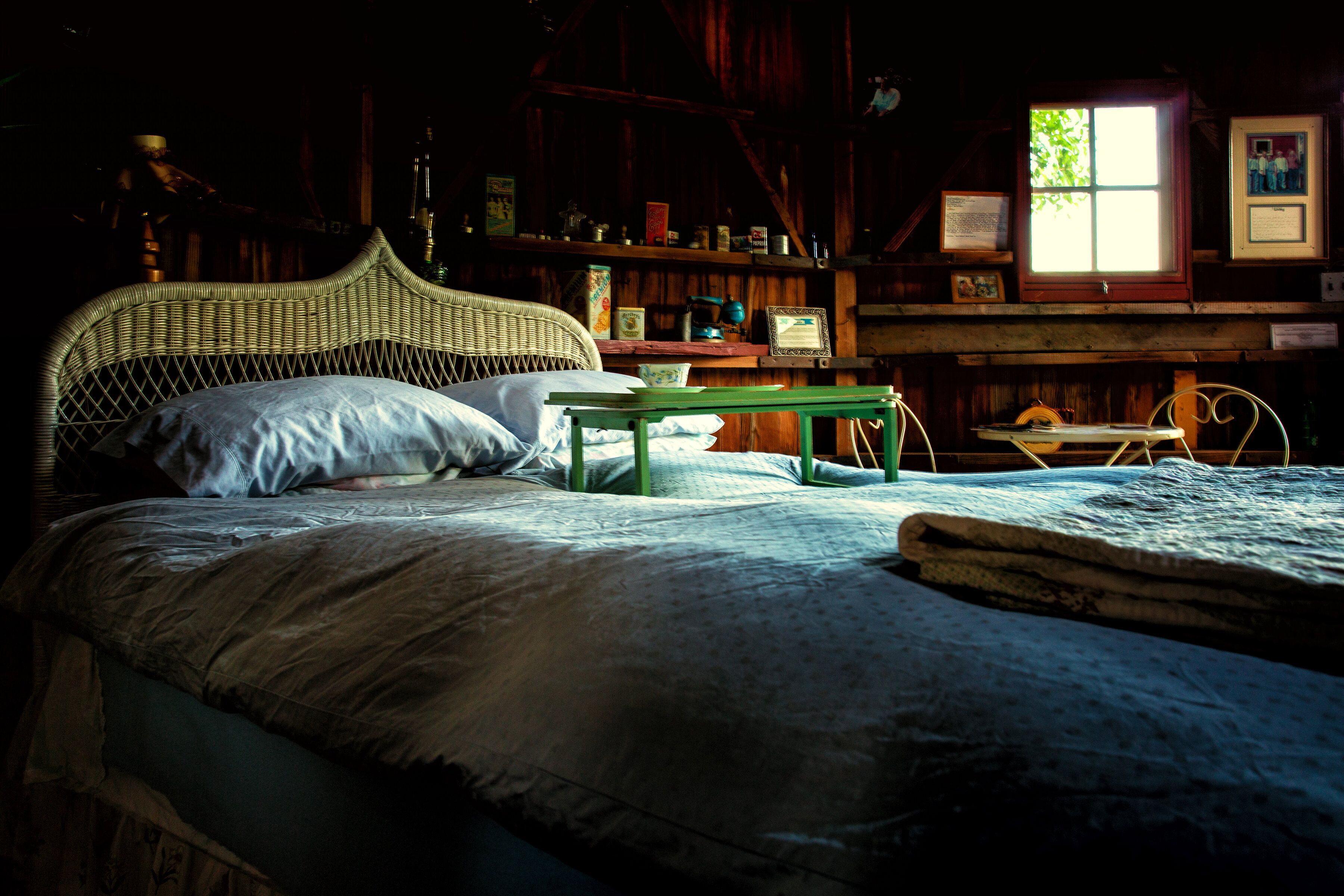 Una habitación rústica de madera con una cama, una mesita y una ventana.