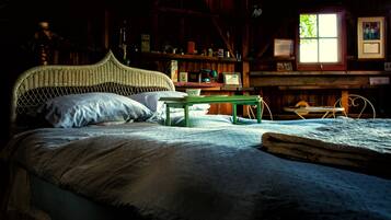 Una habitación rústica de madera con una cama, una mesita y una ventana.